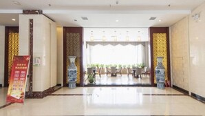 A hotel lobby with a reception desk, a large vase, and a dining area in the background. - Haiyue Junlan Hotel (Huangshan City)