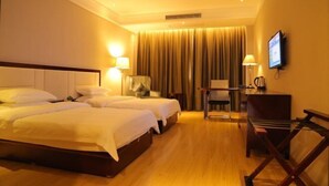 A hotel room with two beds, a desk, a chair, a television, and a window with curtains. - Haiyue Junlan Hotel (Huangshan City)