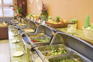 Een buffet met diverse themastands, een keur aan fruit en decoratieve planten.