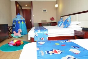 Habitación de hotel con cama, escritorio, silla, mesita pequeña y una silla con dosel, además de un caballo de juguete.