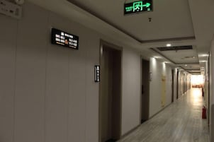 A hotel corridor with directional signs, a fire extinguisher, and a visible door.