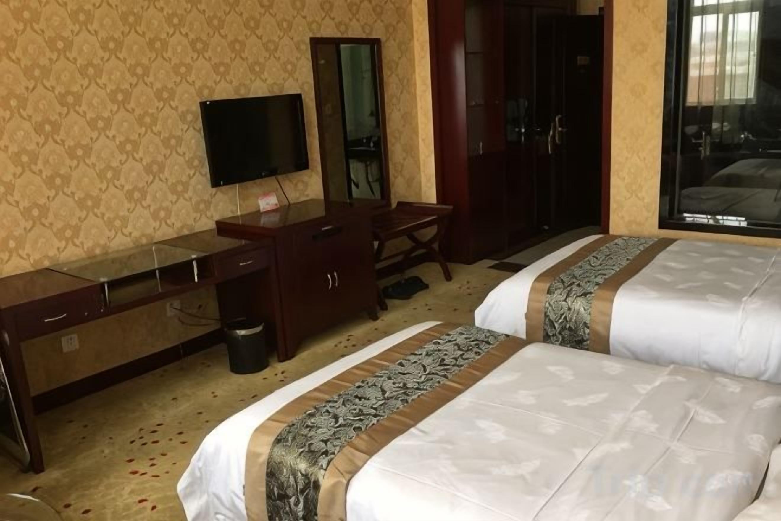 A hotel room with a bed, a desk, a television, and a mirror.