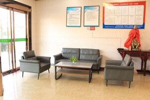 Zona de recepción con un sofá, dos sillones, una mesa de centro y una estatua.