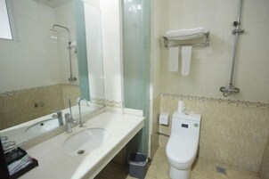 Un baño con lavamanos, espejo, inodoro y toallero.