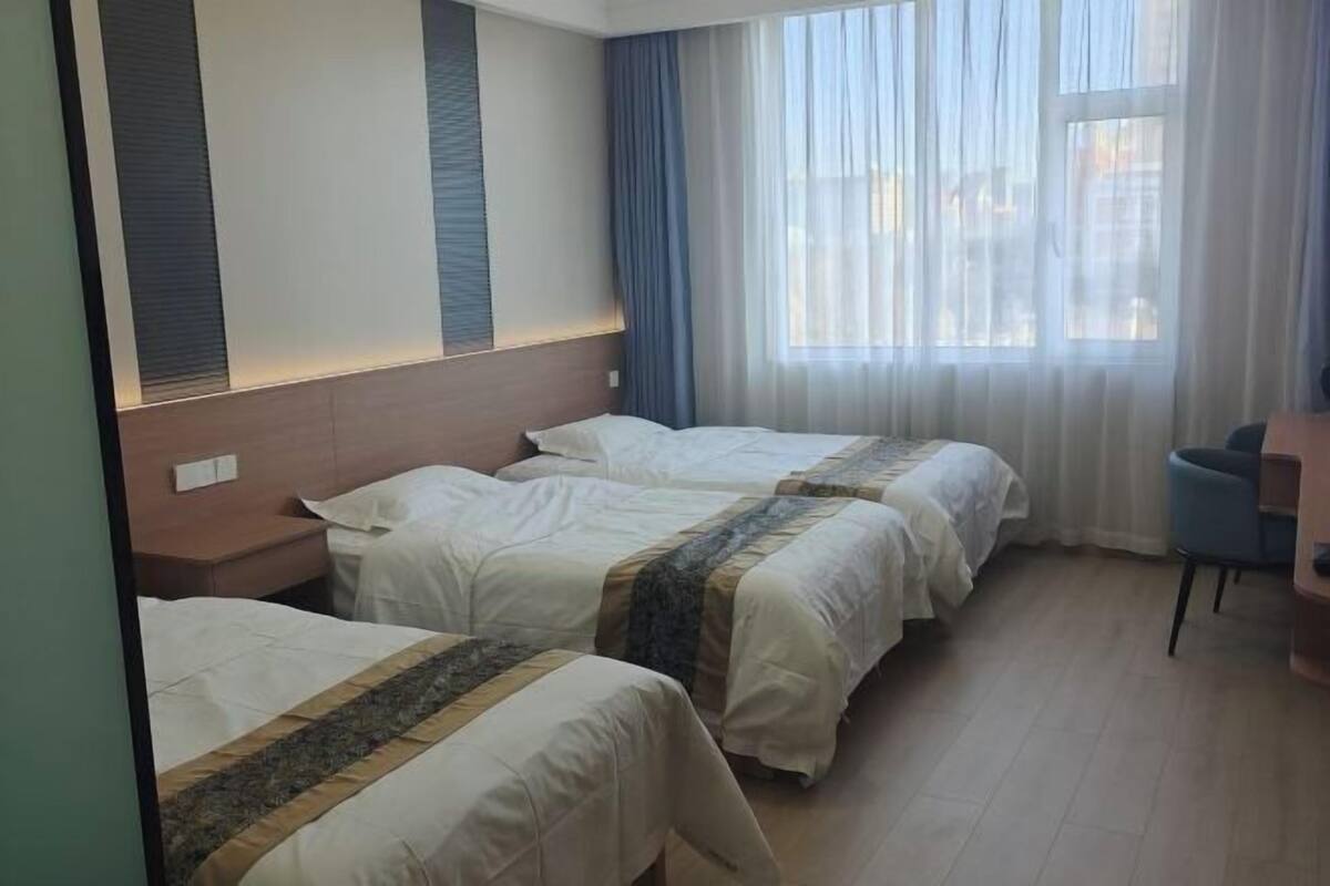A hotel room with two beds, a desk, and a window with curtains.