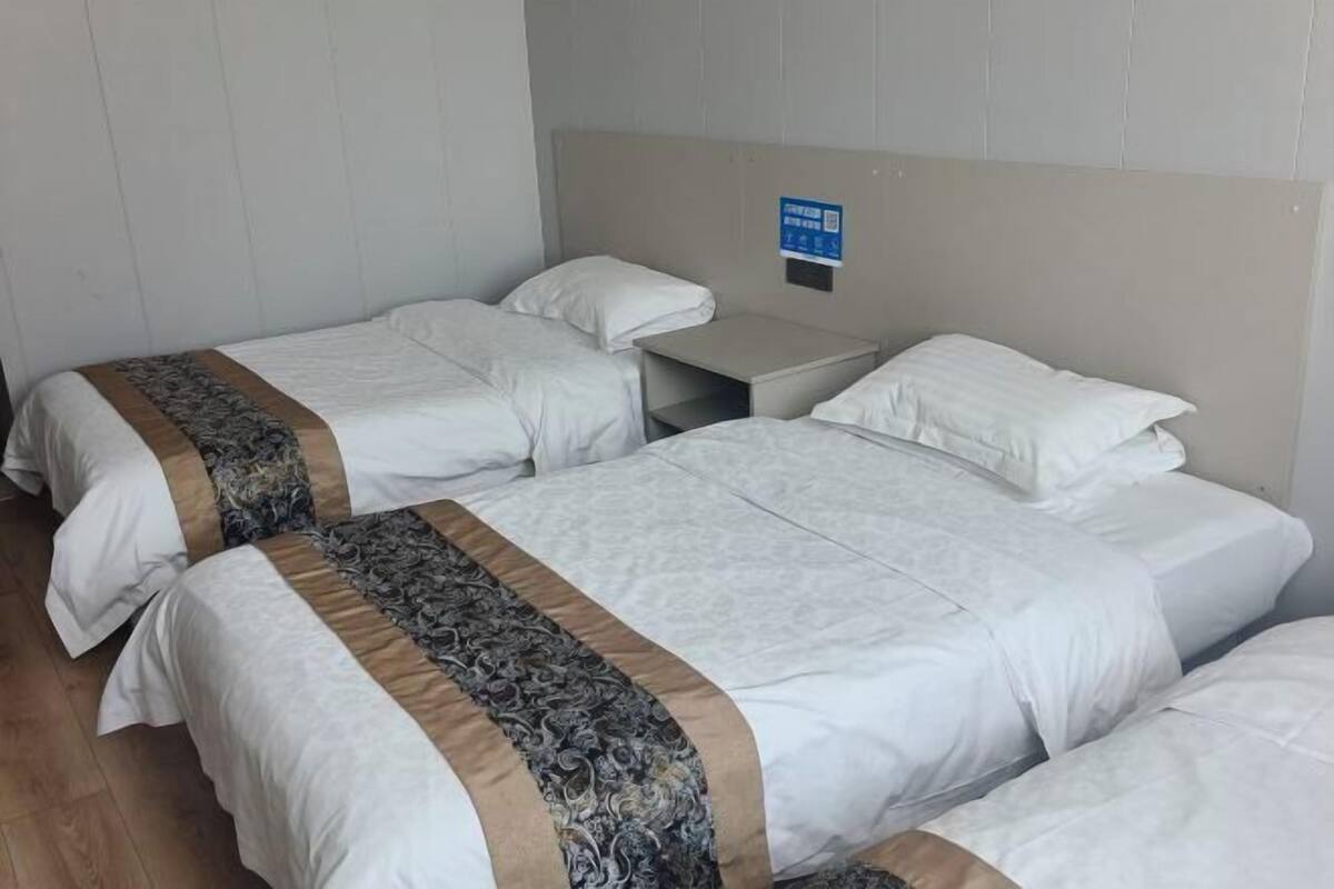 A hotel room with two single beds, a nightstand, and a headboard with a sign.