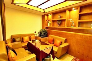 A room with a sofa set, a coffee table, and a wooden shelving unit with decorative items. - Baima Hotel (Damxung)