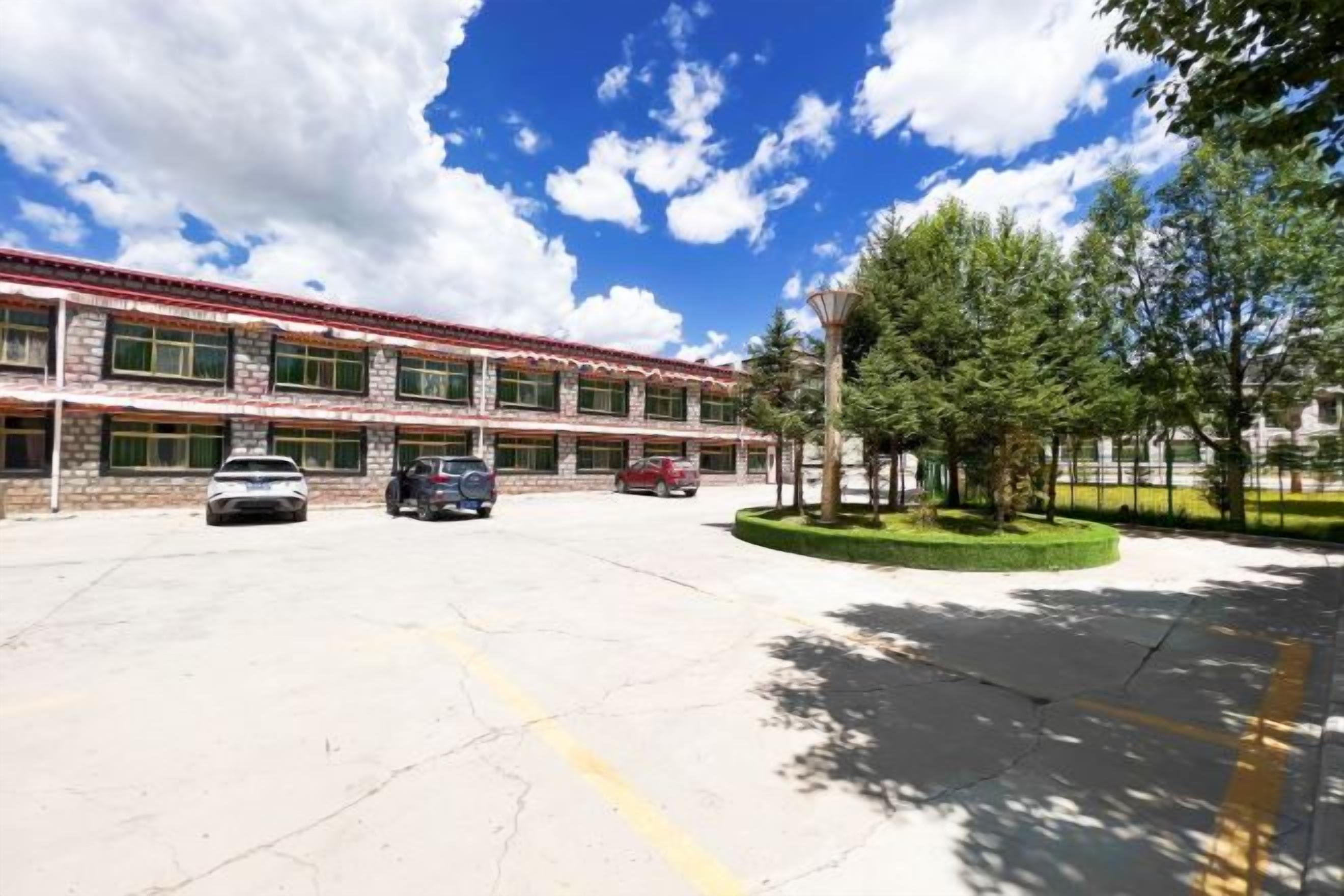A school building with a parking lot, a few cars, and a clear sky.