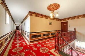 A corridor with a red carpet, a wooden door, and a staircase with a railing. - Baima Hotel (Damxung)