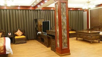 A hotel room with a large bed, wooden furniture, a television, and a decorative pillar.