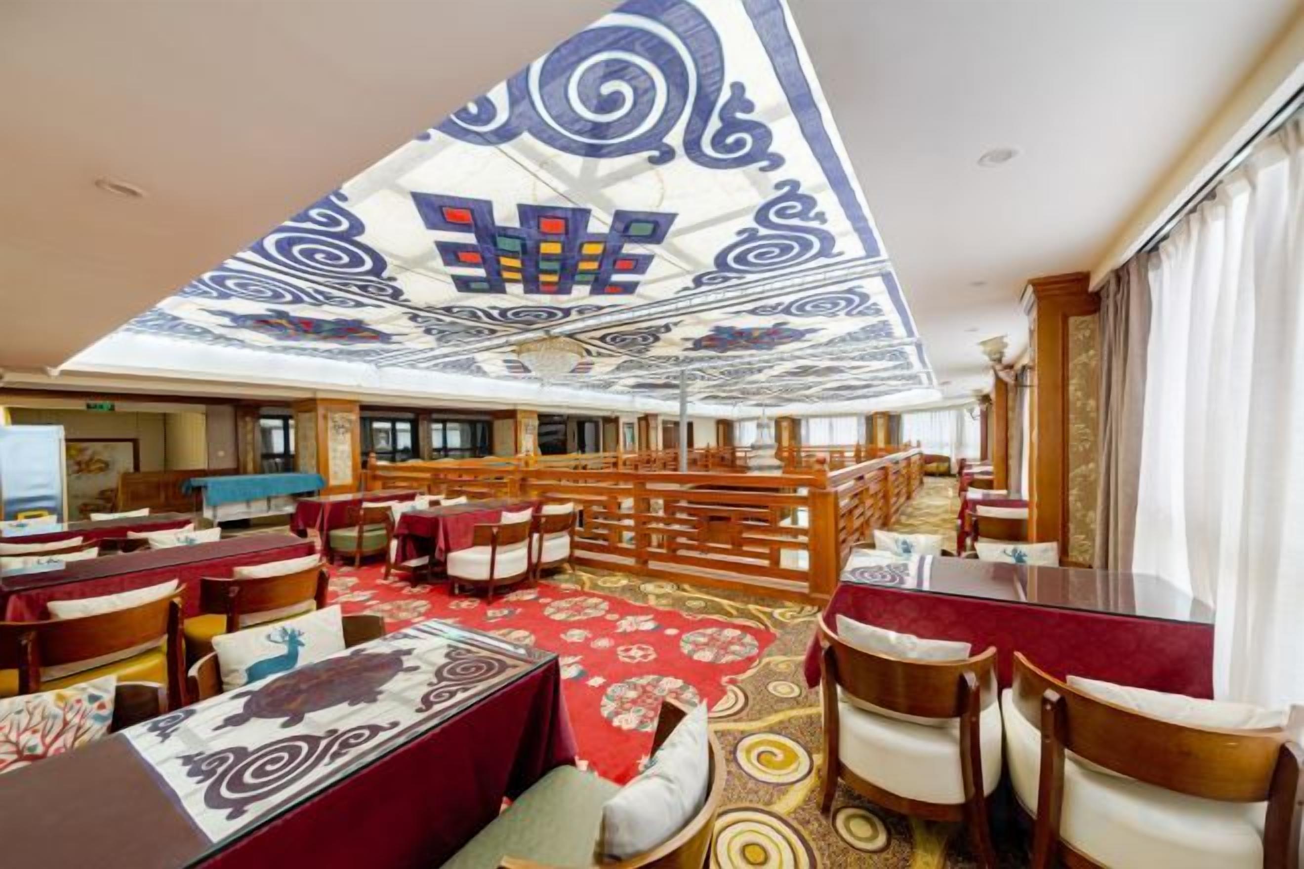 Een hotel lobby met een hoge plafond, een gedessineerd plafond en een centrale trap.