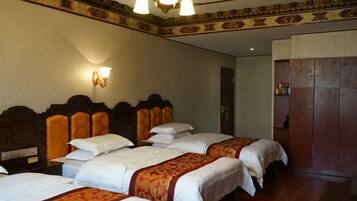 A hotel room with four beds, wooden headboards, and a chandelier.