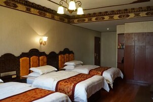 Habitación de hotel con cuatro camas, cabeceras de madera y una araña.