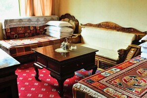 A traditional room with a bed, a wooden table with a teapot, and a patterned carpet. - Baima Hotel (Damxung)