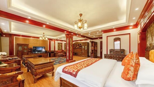 Una habitación de hotel espaciosa con una cama grande, muebles de madera, un televisor y un candelabro.