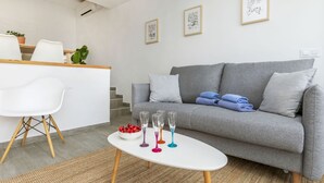 Una sala de estar moderna con un sofá gris, un sillón blanco y una pequeña mesa blanca con vasos de colores.