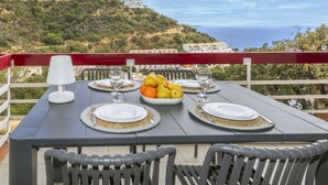 Una mesa para dos con vistas al mar y colinas al fondo.