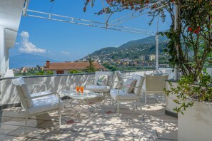 A rooftop terrace with outdoor seating and a view of a coastal town.