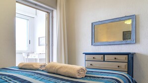 A bedroom with a bed, a dresser, a mirror, and a window.