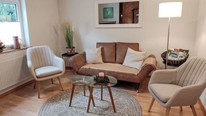 A living room with a brown sofa, two armchairs, a glass coffee table, a patterned rug, a potted plant, a framed picture, and a floor lamp. - Neles Kate am Diemelsee by Interhome (Marsberg)
