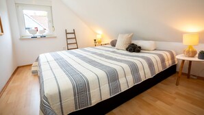 A bedroom with a large bed, a window with a view of a house, a small table with a lamp, and a ladder against the wall. - Neles Kate am Diemelsee by Interhome (Marsberg)