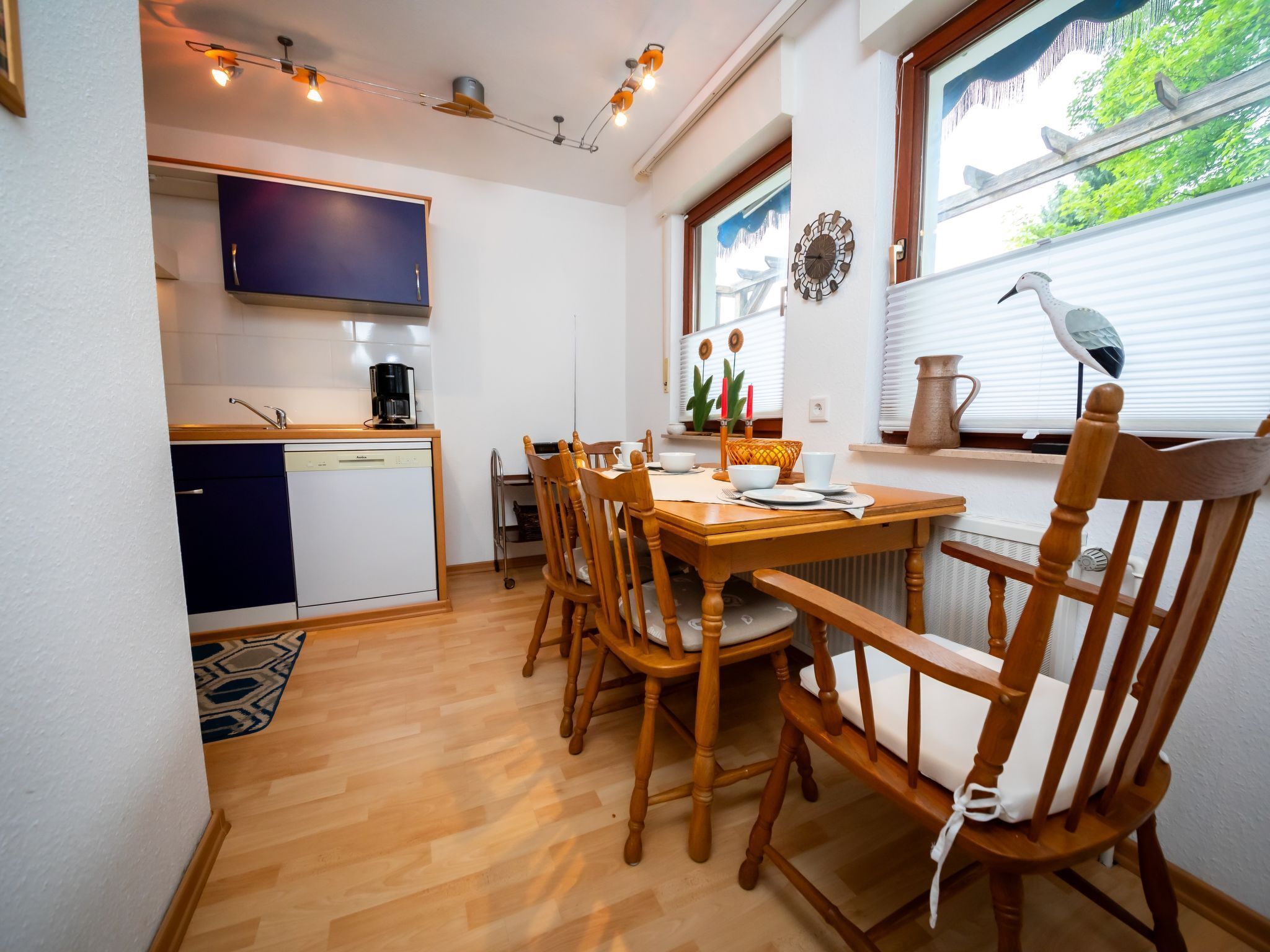Une cuisine compacte avec un coin repas, des chaises en bois et un téléviseur placé au-dessus du comptoir.