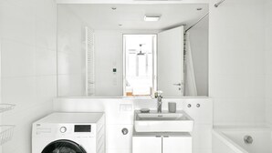 Un baño moderno con lavadora, lavamanos y bañera.