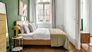 Ein Schlafzimmer mit einem Bett, einem Nachttisch, einer Lampe und einem Fenster mit Vorhängen.