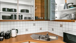 Eine moderne Küche mit weiß gefliestem Fliesenspiegel, Spüle aus Edelstahl und Holzschränken.