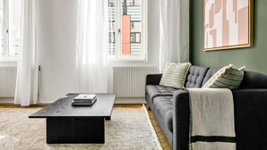 Ein modernes Wohnzimmer mit einer dunklen Couch, einem Couchtisch und einem großen abstrakten Gemälde an der Wand.