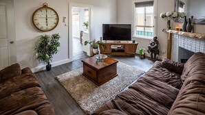 A living room with a large clock, a television, and a fireplace. - Cabos On Currajong! (Parkes)