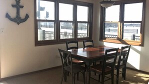 Un comedor con una mesa y sillas de madera, ventanas amplias con vistas a un paisaje nevado y un ventilador de techo.