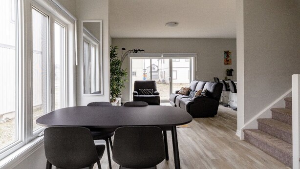 A spacious living area with a dining table, chairs, a sofa, and a staircase. - Luxury Entire house mins Niagara falls & Brock uni (Thorold)