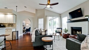 Una sala de estar moderna con chimenea, televisor y comedor con una mesa de centro.