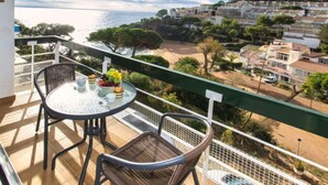 Un balcón con mesa y sillas con vistas a un pueblo costero.