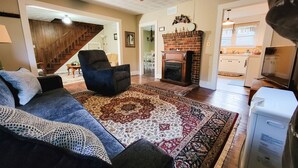 A living room with a sofa, a chair, a fireplace, and a ceiling fan. - New River Cottage (Crumpler)