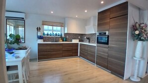 A modern kitchen with wooden cabinets, a built-in oven, and a large window.