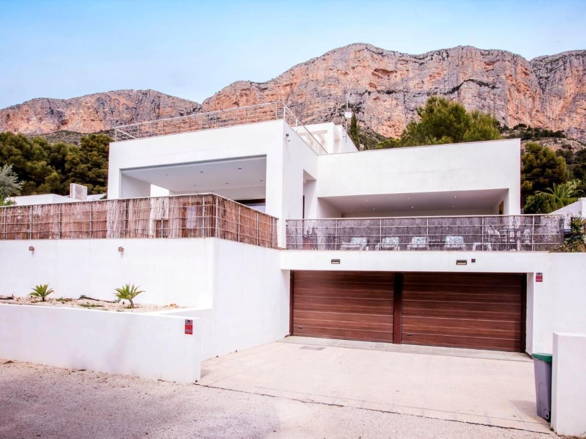 A modern two-story house with a flat roof, a large garage, and a balcony.