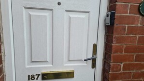 Una puerta blanca con manija y placa de latón con el número 187.