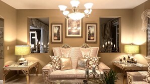 Ein luxuriöses Wohnzimmer mit einer bequemen Couch, verzierten Beistelltischen und einem Kronleuchter.