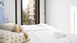 A hotel room with two beds, a balcony, and a view of the cityscape.
