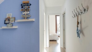 A hallway with a blue wall, a bed in the background, and a wall-mounted coat rack.