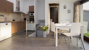 A modern kitchen with white cabinets, a built-in oven, and a dining area with a white table and chairs.