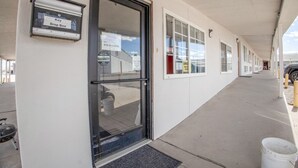 Un motel doté d’une boîte aux lettres pour déposer les clés, d’un panneau indiquant la présence d’un système de sécurité et d’une rangée de chambres avec des fenêtres.