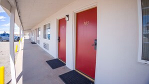 Un couloir avec des portes rouges numérotées 104 et 105, qui donnent accès à des pièces.