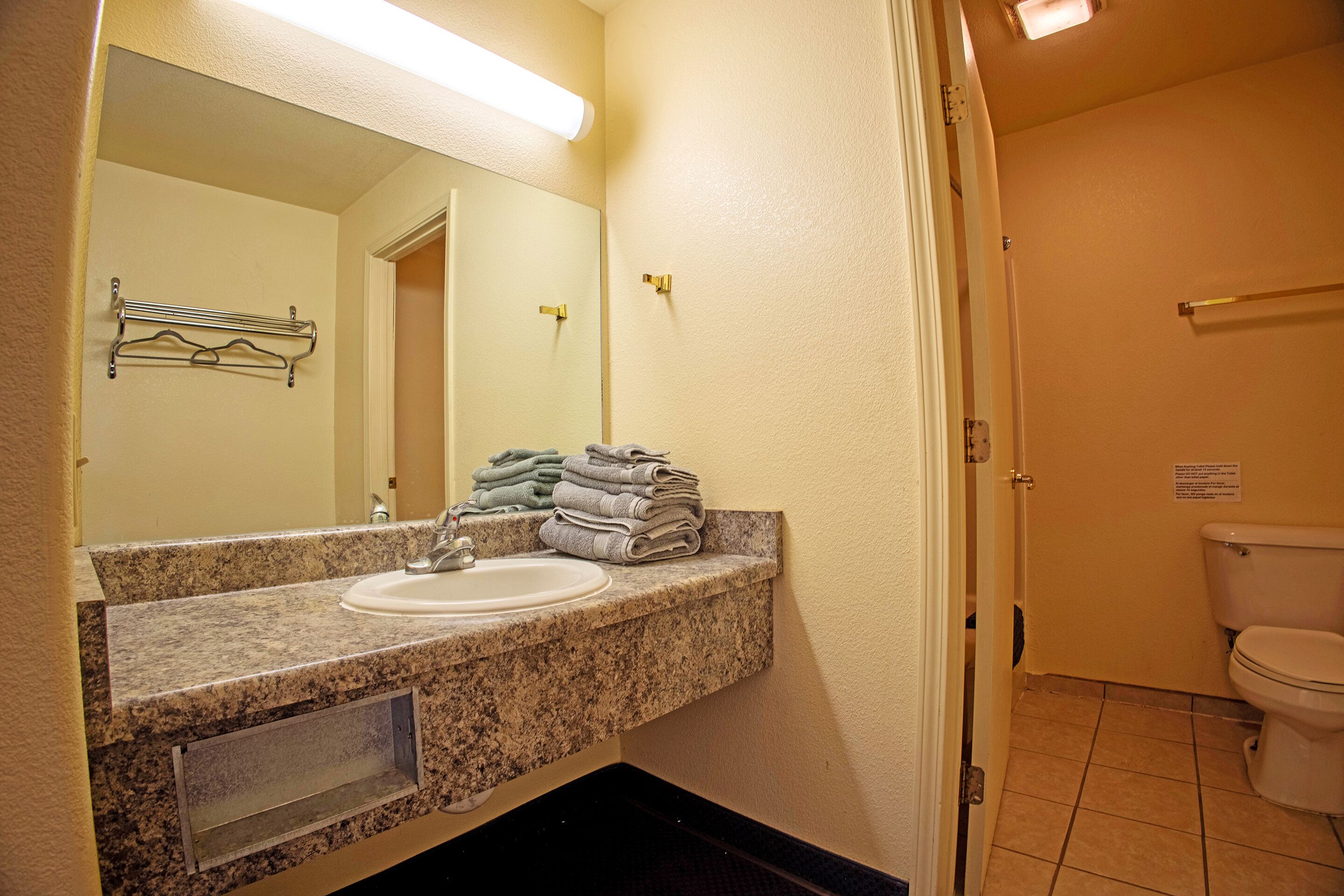 A bathroom with a sink, mirror, towel rack, and toilet.