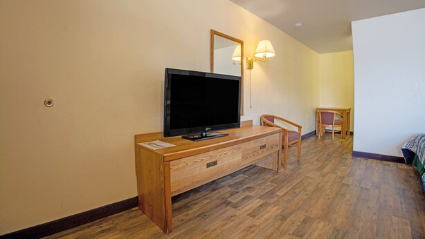 Une chambre d’hôtel avec un bureau en bois, une télévision, une chaise et un lit.