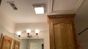 Une salle de bain avec des meubles en bois, un miroir et un luminaire placé au-dessus du miroir.