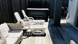 Een terras met rieten meubilair, een hottub en een houten dek.
