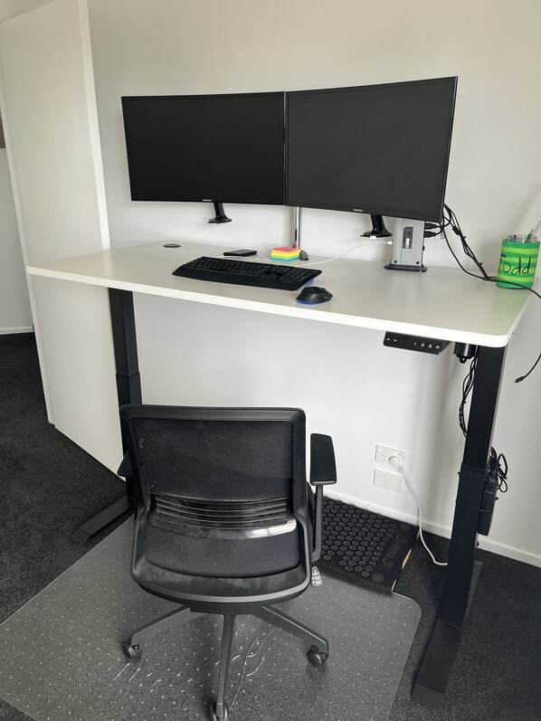 A modern office desk with dual monitors, a keyboard, a mouse, and a chair.